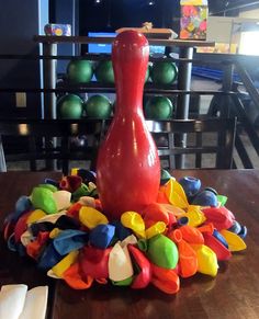 a red vase sitting on top of a table filled with colorful plastic letters and shapes