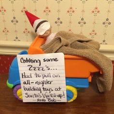 a toy with a note attached to it sitting on top of a wooden table next to a wall