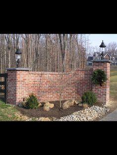 a brick wall and gate with trees in the background