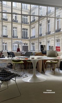 a room filled with lots of windows and furniture in front of large glass windows that look out onto the street