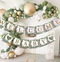 a welcome baby banner with balloons and greenery