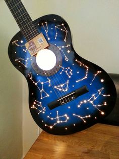 a blue guitar with stars on it sitting on top of a wooden table next to a wall