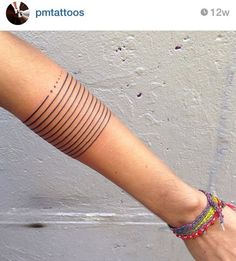 a woman's arm with a tattoo on it and a bracelet around her wrist