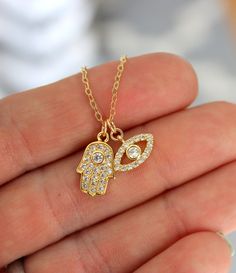 "This is a gorgeous little gold filled evil eye hamsa double charm necklace. These sparkling little charms come together on a shiny 14kt gold filled cable chain. Both charms are 14kt gold filled, have a small clear pave crystals. Hamsa measures 15x9mm and evil eye 13x8mm. PLEASE CHOSE YOUR LENGTH. These charms are even prettier in person! Comes in a cute gift box! Model is wearing a 16\" length in photo." 14kt Gold Jewelry, Gold Evil Eye Necklace, Hamsa Necklace Gold, Evil Eye Hamsa, Evil Eye Necklace Gold, Preppy Jewelry, Gold Hamsa, Hamsa Necklace, Jewelry Accessories Ideas