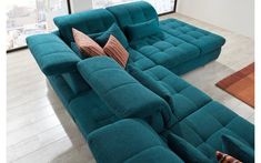 a large blue couch sitting on top of a wooden floor next to a tall window