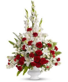 a white vase filled with red and white flowers