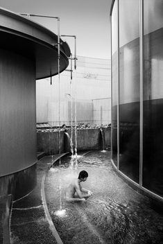 black and white photograph of a boy playing in the water at an indoor swimming pool