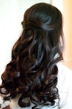 the back of a woman's head with long dark brown hair and wavy curls