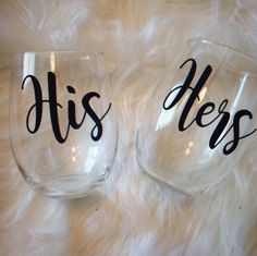 two wine glasses with the words his and hers written on them sitting on a fur surface