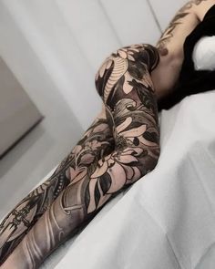 a woman laying on top of a bed covered in lots of black and white tattoos