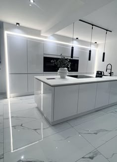 a white kitchen with marble flooring and lights on the ceiling, along with an island in the middle