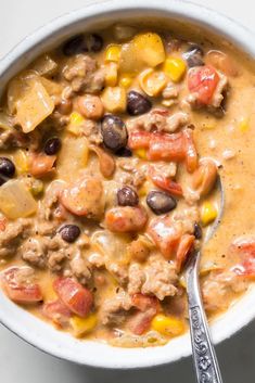 a white bowl filled with beans, corn and meat soup on top of a table