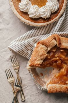 two pies sitting on top of plates next to forks and silver utensils