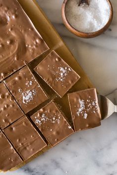 chocolate squares with sea salt on top sitting on a marble counter next to a spoon