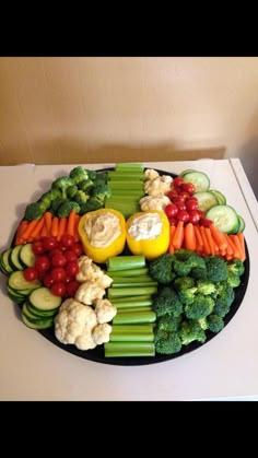 a platter filled with vegetables and dips on top of a white countertop