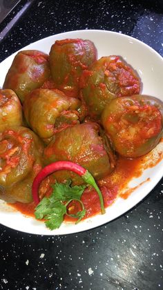 a white plate topped with stuffed peppers covered in sauce