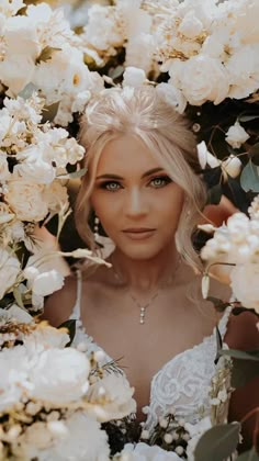 a woman with blonde hair and blue eyes is surrounded by white flowers in her wedding dress