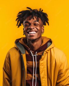 a young man with dreadlocks smiling and looking at the camera while standing against a yellow background