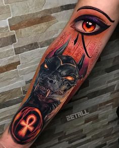 an eye and demon tattoo on the arm