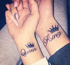 two people with matching tattoos on their wrists holding hands and the words queen and king written in cursive font