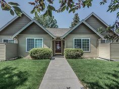 a house that is in the middle of some grass and has bushes on each side