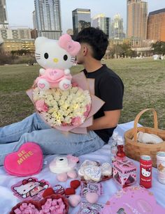 a man sitting on the ground with a bouquet of flowers and hello kitty stuffed animal