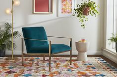 a blue chair sitting on top of a rug next to a potted plant