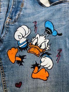 a pair of jeans with donald and daisy painted on the back of one jean jacket