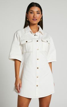 Leilani Mini Dress in Ecru - Transform your wardrobe with the effortlessly chic Leilani Mini Dress in Ecru - the perfect blend of denim and cream. This shirt dress is a must-have for any fashion-forward woman looking to elevate her casual ensemble game. The short sleeves and button-up design add a touch of edginess while still maintaining an air of sophistication. Whether you're running errands or meeting up with friends, this versatile dress will become your go-to choice for any occasion. Don't Knee-length Cotton Shirt Dress With Buttoned Pockets, Cotton Short Sleeve Shirt Dress With Buttoned Pockets, Short Sleeve Denim Dress For Day Out, Classic Cotton Denim Dress With Button Closure, Cotton Button-up Shirt Dress With Rolled Sleeves, Collared Cotton Shirt Dress With Button Closure, Cotton Denim Dress With Short Sleeves For Day Out, Cotton Collared Shirt Dress With Button Closure, Short Sleeve Denim Dress With Pockets