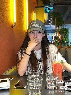 a young woman sitting at a table with drinks in front of her