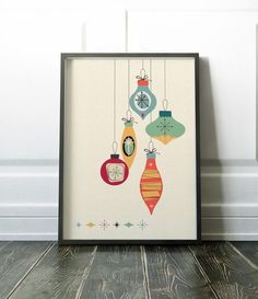 a framed christmas ornament art print hanging from strings on a wall next to a wooden floor