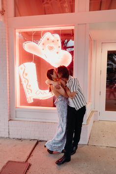 a man and woman kissing in front of a store window