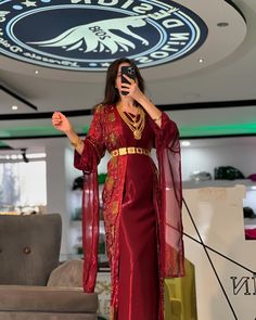 a woman in a red dress holding a cell phone up to her face and standing on a stage