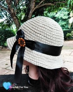 a close up of a person wearing a hat with a black ribbon and flower on it