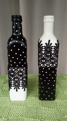 two black and white vases sitting on top of a green tablecloth covered floor