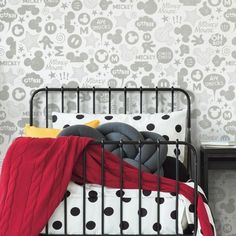 a bedroom with mickey mouse wallpaper and black metal bed