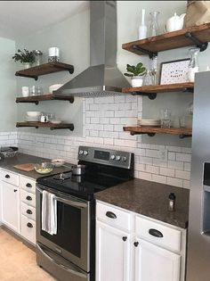 a kitchen with white cabinets and open shelving above the stove top oven is shown