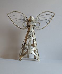 an angel statue made out of strips of paper and metal with writing on it's wings