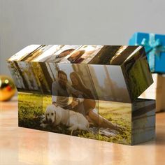 a photo block is sitting on a table next to a gift box with the image of two people and a dog