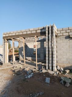 a building under construction in the middle of a dirt field with rocks and rubble around it