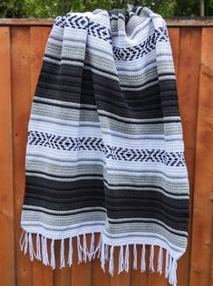 a black and white blanket hanging on a wooden fence