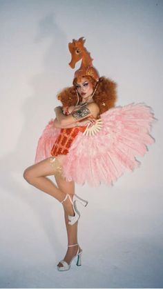 a woman in a pink dress is posing with a horse on her head and legs