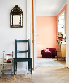 a room with two chairs, a table and a mirror on the wall in it