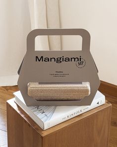 a stack of books sitting on top of a wooden table next to a white curtain