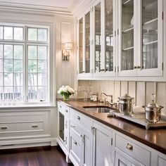 a kitchen filled with lots of white cabinets and wooden counter tops next to a window