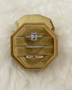 two diamond rings sitting on top of a velvet ring box with white furnishing