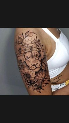 a woman's arm with a lion and flowers tattoo on the left side of her body