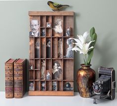 an old fashioned camera, vase with flowers and two books on a table next to it