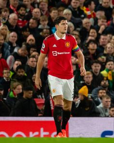 a soccer player is standing in front of a crowd with his head turned to the side