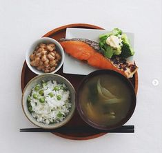 a wooden plate topped with rice, meat and veggies next to chopsticks